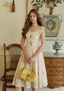 Cream lace embroidered fit-and-flare dress with square neckline and ruffled cap sleeves.