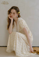 Lace tea dress in pale yellow with V-neck lace bodice and gathered skirt, reclining pose