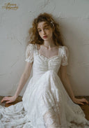 White lace dress with square neckline, short puff sleeves, and gathered skirt volume.