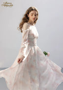 Floral tiered dress in pale pink with ruffled shoulders, twirling side view
