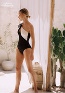 Side view of black one-shoulder rosette swimsuit with white panel