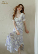 Lavender floral midi dress with short puff sleeves and gathered hem, standing full view.
