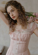 Pale pink dotted dress with ruffled neckline, lace front panel, and pearl necklace
