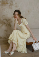 Sleeveless cream dress with lace-trim neckline and layered ruffle hem