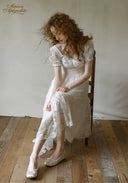 White lace dress with square neckline, short puff sleeves, and full skirt with lace detailing.