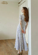 Lavender floral midi dress with short puff sleeves and gathered skirt, back three-quarter view.