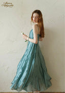 Teal satin midi dress with ruched bodice and spaghetti straps, angled profile