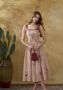 Pink linen maxi dress with floral embroidery and burgundy straps, standing full-length