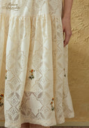 Close-up of cream lace embroidered skirt with diamond pattern and floral accents.