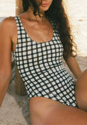 Black-and-white checkered one-piece swimsuit with scoop neckline and thin straps, close-up.