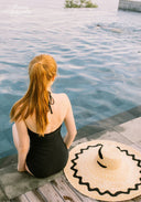 Black one-piece swimsuit back view with halter straps and low, open-back neckline.