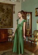 Green satin long dress with lace V neckline and short puff sleeves, draped skirt, side profile