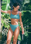 Woman wearing a blue bikini set with tropical plants in the background