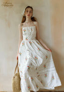 Secret Garden dress with spaghetti straps, white floral print, tiered skirt; straw bag