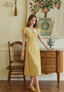 Yellow embroidered midi dress with peter pan collar, button front, and embroidered pockets