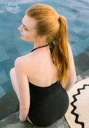 Black one-piece swimsuit with low back and halter strap ties.