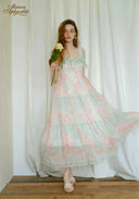 Woman in a floral dress holding a yellow flower against a white curtain backdrop