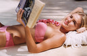 Woman in pink bikini reading a book on a sandy beach