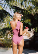 Pink one-shoulder swimsuit with crisscross back tie and high-cut leg